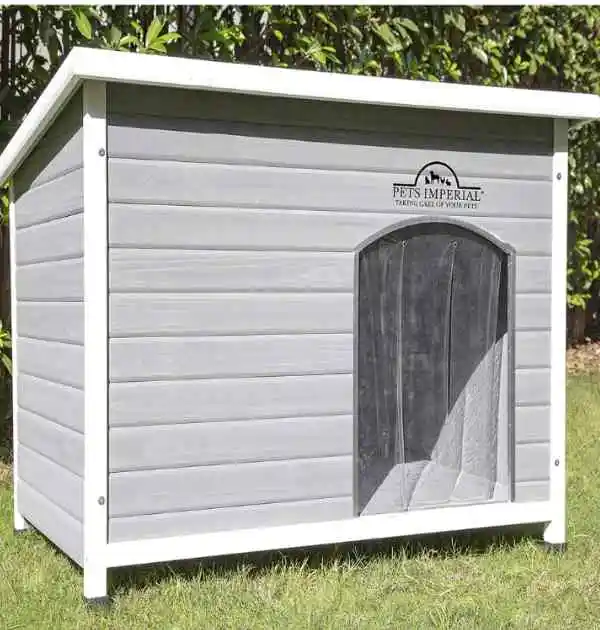 A spacious wooden dog kennel with an open door, nestled in lush grass, providing a cozy retreat for pets.